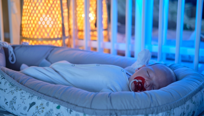 Portrait of a baby boy aged one month sleeping in a crib.