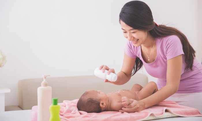 Portrait of mother applying powder to her baby after bath.