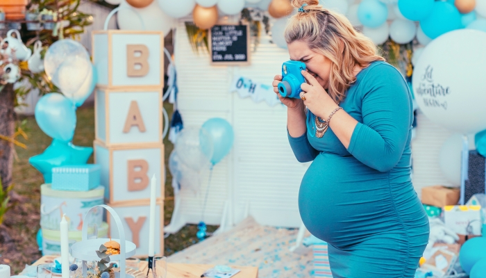 Pregnant woman taking photos of a decorated table for baby shower.