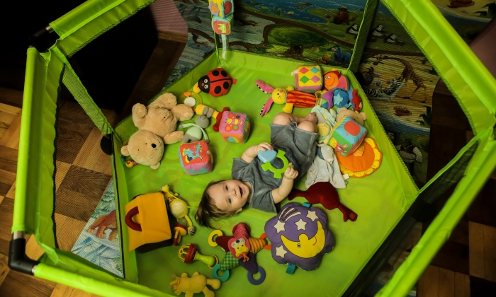 Smiling boy looking at the camera in a green playpen.