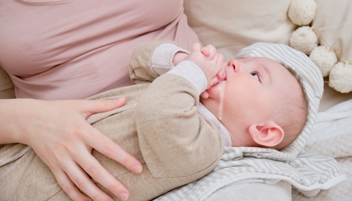 A mother woman holds an infant baby to regurgitate excess air after breastfeeding.