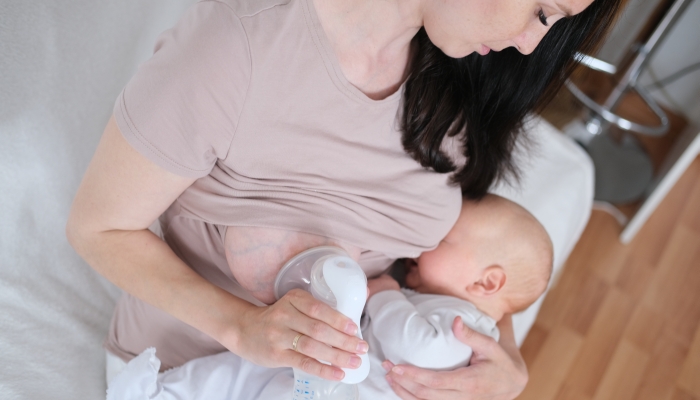 A young woman holds a newborn baby in her arms and breastfeeds.