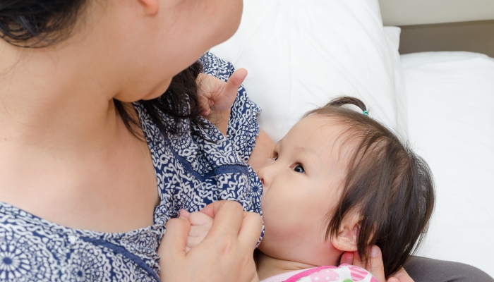 Asian mother breast feeding her daughter.