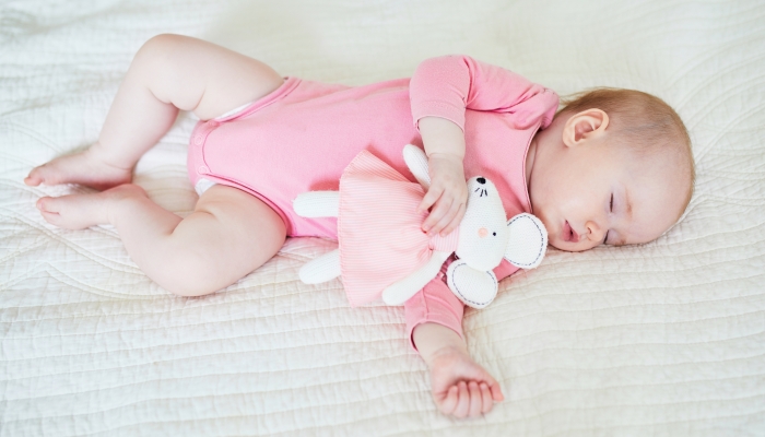 Baby girl having a nap with her favorite mouse toy. Little child sleeping on bed with comforter. Sleep.