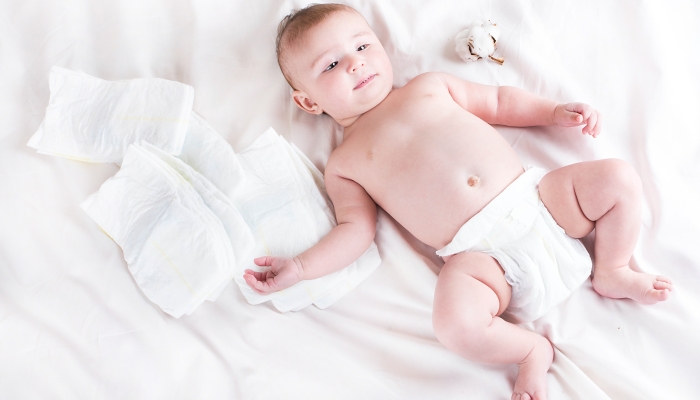 Baby in diaper on a white background with a branch of cotton.