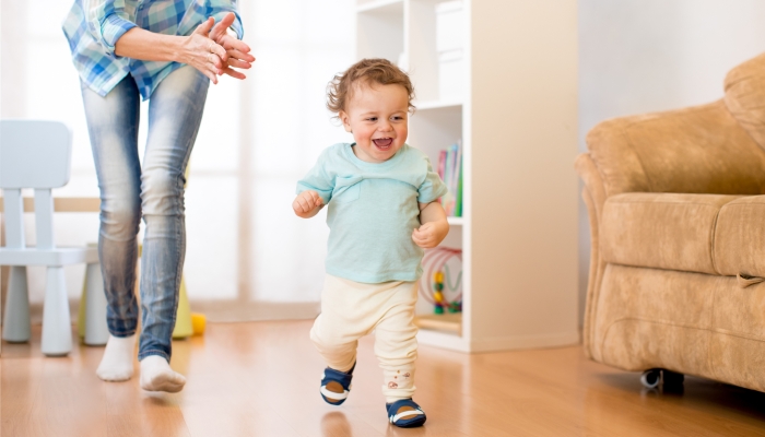 Baby toddler have a fun running in living room with his mother.