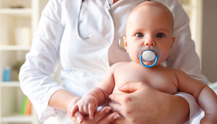 Baby with pacifier in mouth at the pediatrician on examining.