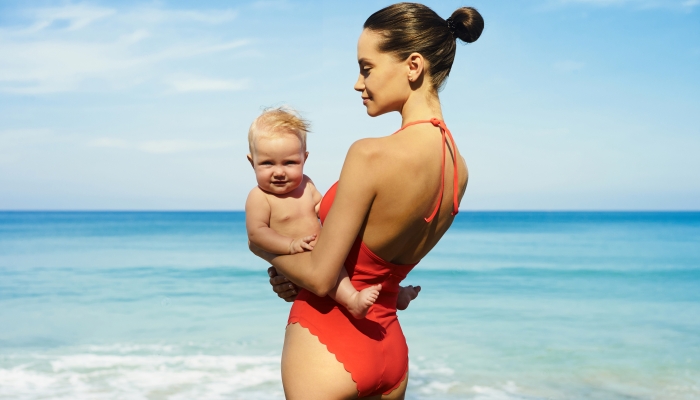Beautiful lady with little baby-girl on the summer beach.