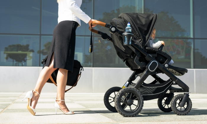 Business mother pushing baby on the way to work.