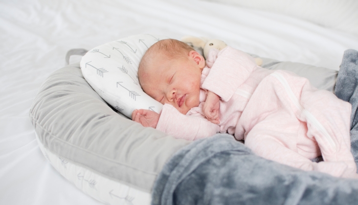 Caucasian Newborn baby sleeping in a baby lounger. Baby nest.