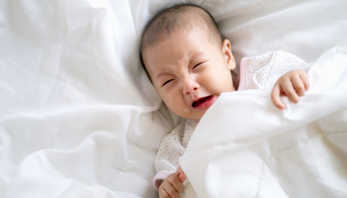 Close up Adorable Asian baby infant girl cry on white bed.