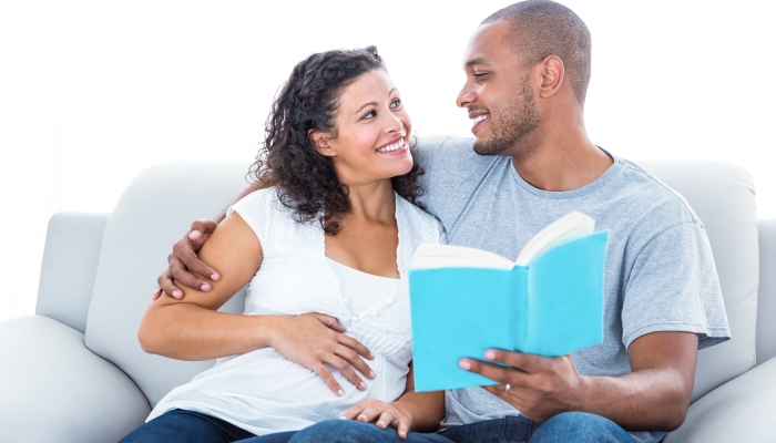 Couple reading book relaxing at home.