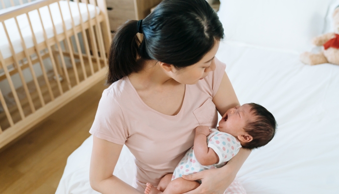 First-time mom cuddling her baby daughter and trying to soothe her.