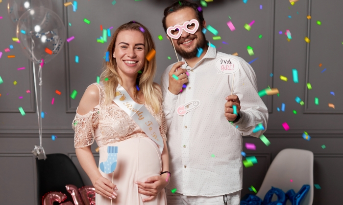 Happy couple holding balloons with inscription boy or girl during gender reveals party.