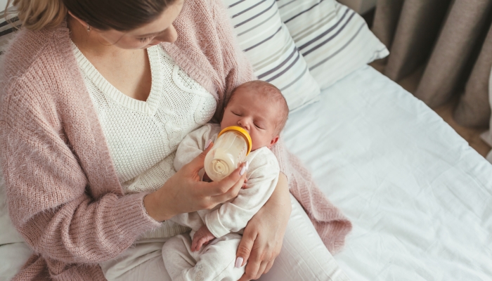 Home portrait of a newborn baby with mother on the bed.