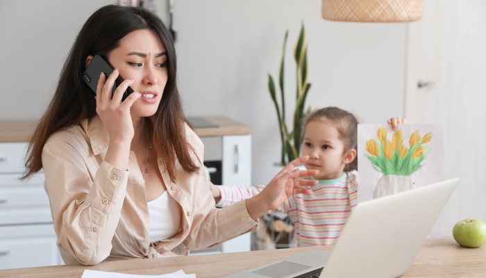 Little daughter keeping mother from her work at home.