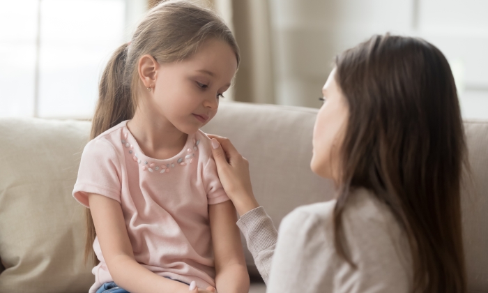 Loving worried mom talking to upset little child girl.