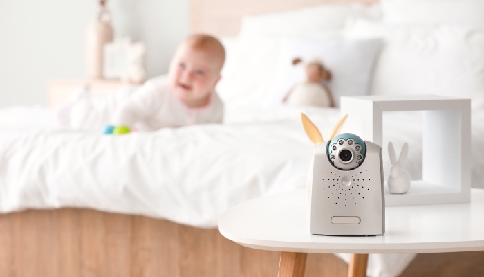 Modern baby monitor on table in room with little child.