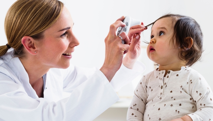 Paediatrician checking baby boy's eyes.