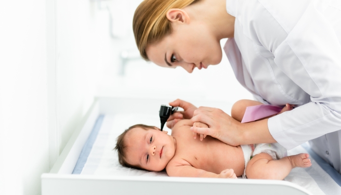 Pediatrician examines 2 week old baby's ear in new pediatric clinic.