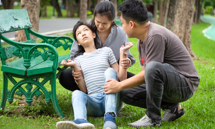 Sick little child girl with epileptic seizures in outdoor park.