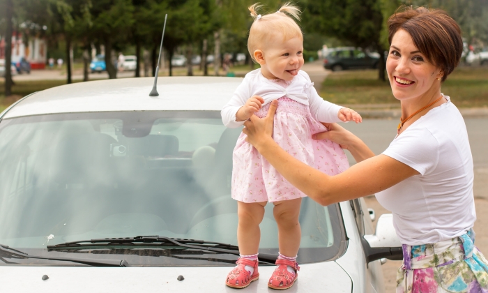 Small cute baby on the car and her mom.