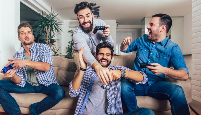 Smiling male friends playing video games at home and having fun.