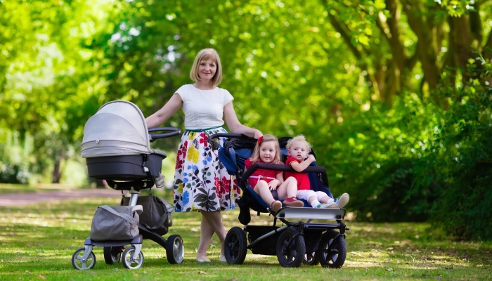 Woman pushing a double stroller for twin boy and girl.