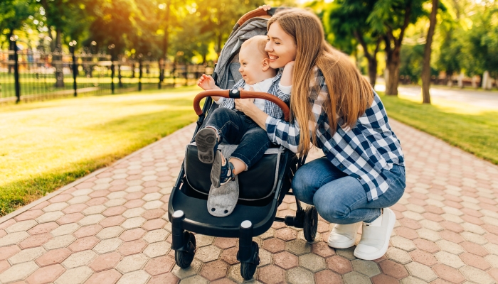 Young beautiful mother, with her little cute child, walking in the park on a sunny summer day.