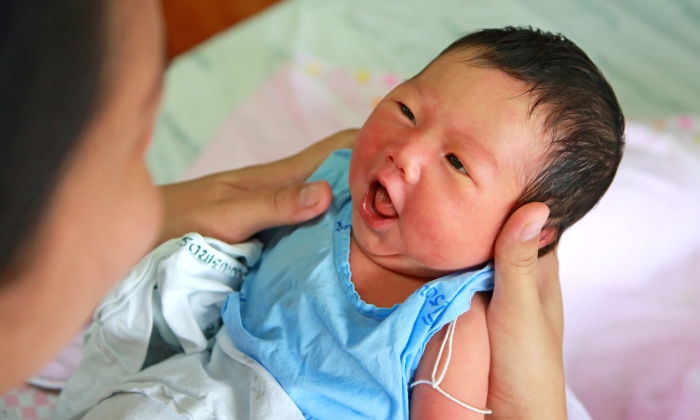 face of baby infant in emotion sign on mother hand.