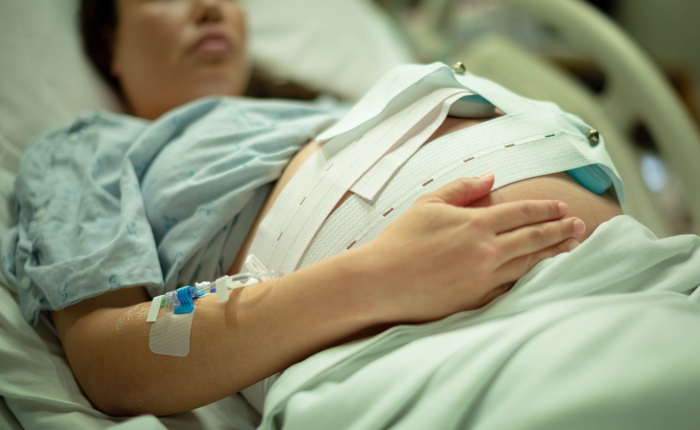 A pregnant woman being induced in the hospital, with iv and contractions monitor.
