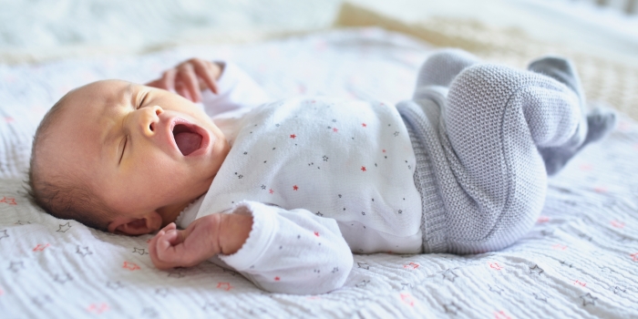 Adorable baby girl sleeping and yawning in bed at home.