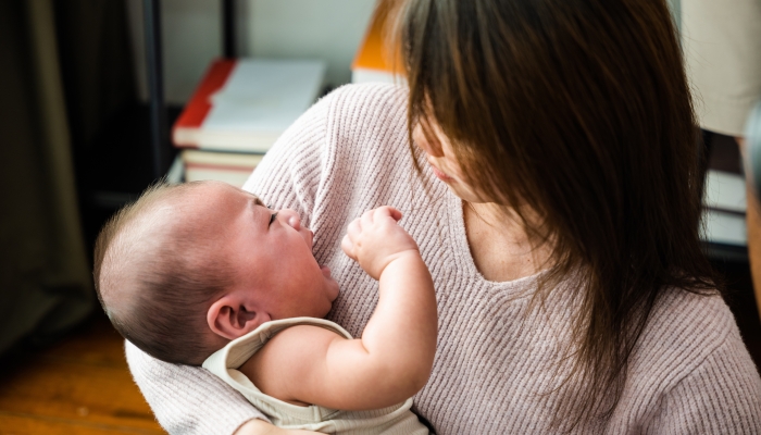 Asian mom holding her crying little baby at home.