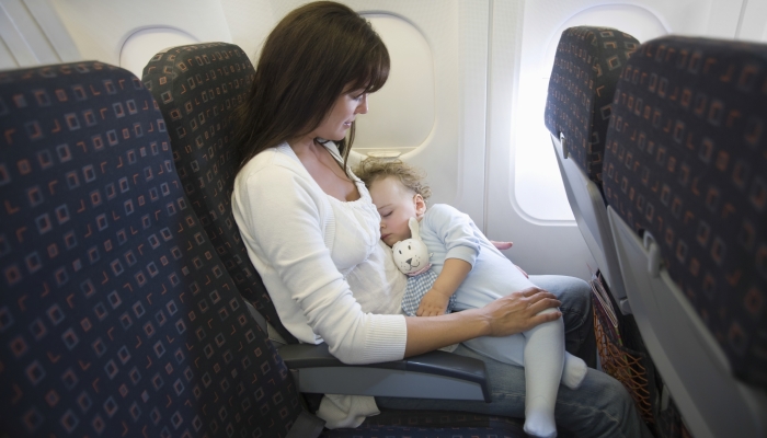 Baby girl sleeping on mother's laps while traveling in airplane.