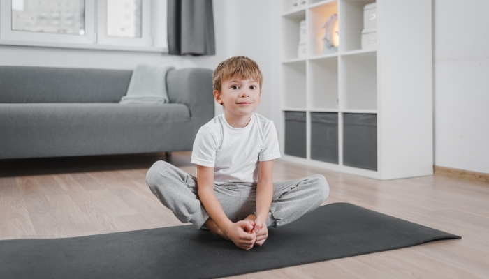 Boy child practicing yoga, doing Butterfly exercise.