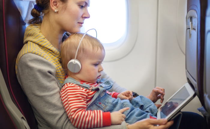 Caucasian mother and toddler son using tablet pc while on board of airplane.