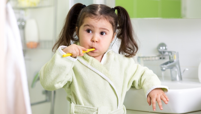 Child little girl brushing teeth in bath.