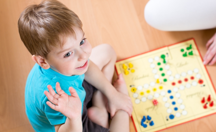 Child playing in board game sitting on floor.