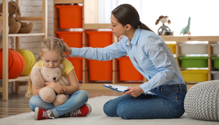 Child psychotherapist working with little girl in office.