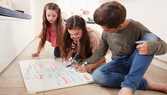 Children Making List Of Chores On Whiteboard At Home.