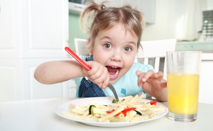 Cute funny kid eating noodles.