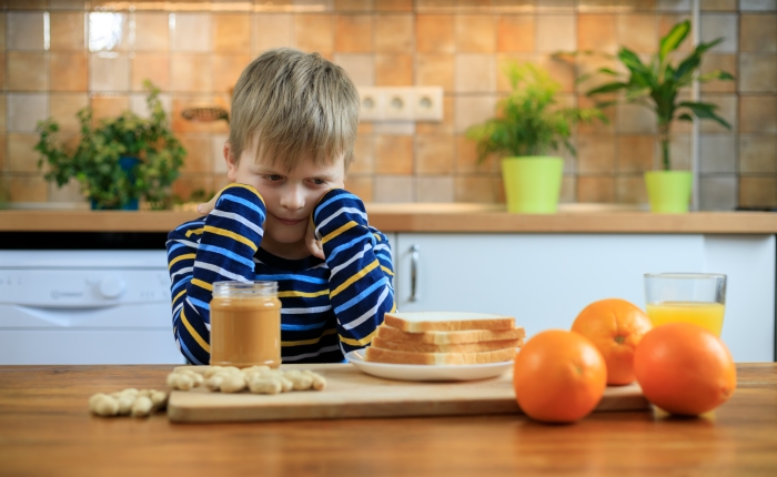 Cute kid girl not wanting to eat healthy food at kitchen.