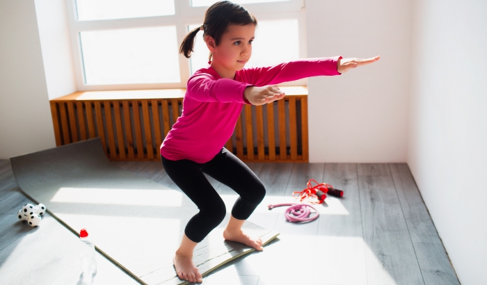 Cute kid is training on a mat indoor.