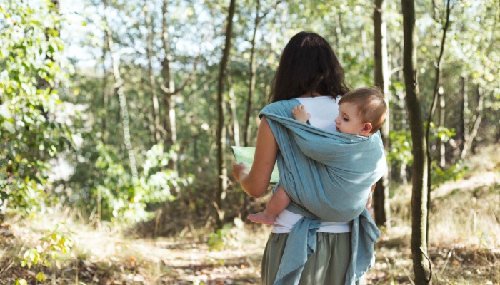 European mother babywearing one year old on a hike in the forest.