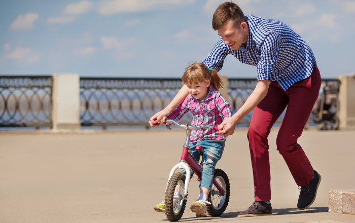 Father Teaching Daughter To Ride Bike.