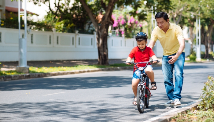 Father watching his son riding a bike.