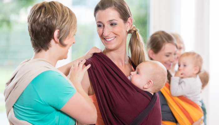 Group of women learning how to use baby slings for mother-child bonding.