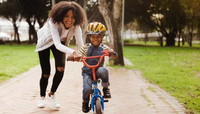 Happy cute boy learn to ride a bike with his mother.