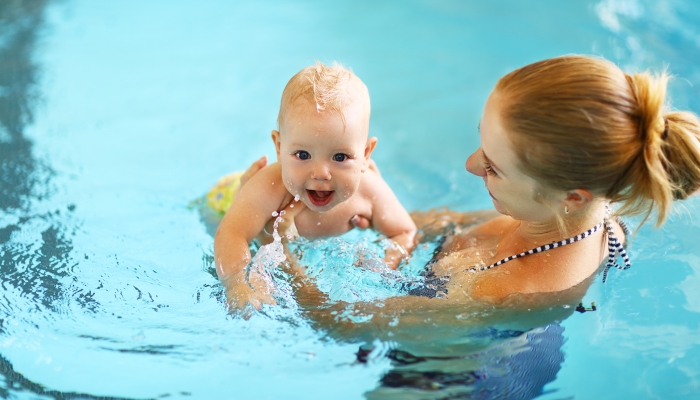 Healthy family mother teaching baby swimming pool.