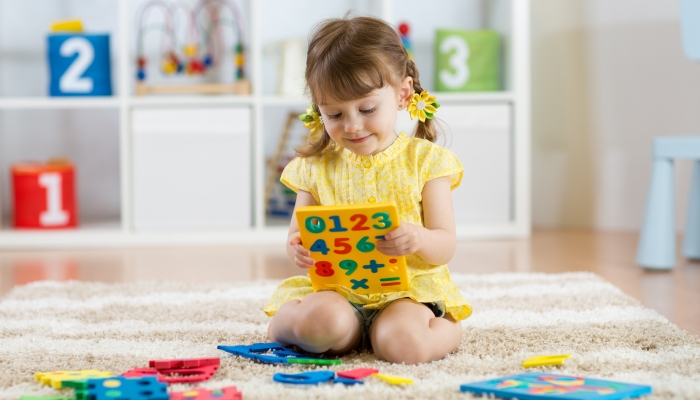 Little girl child playing with lots of colorful plastic digits.